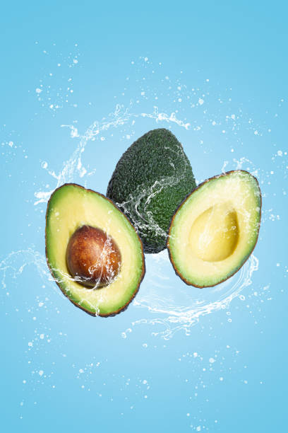 istock Avocado slice with water splash isolated on blue blackground. 1307265240