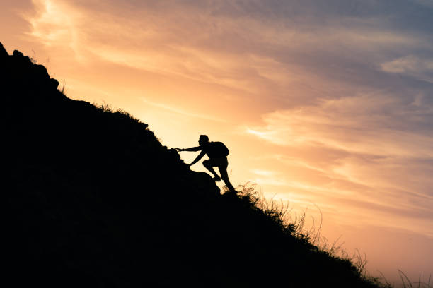 istock Men climbing up the mountain at sunset. 1307265380