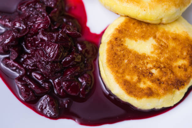 frühstück und leckeres konzept - pfannkuchen aus hüttenkäse mit marmelade, blauem hintergrund. - cheesecake syrup cottage cheese cream stock-fotos und bilder