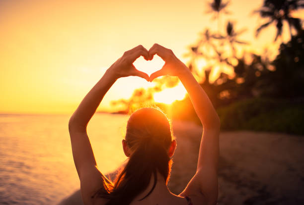 istock Woman making heart shape at sunset. 1307265396