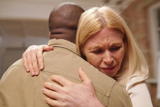 Suffering mature blond female embracing another patient of mental support group