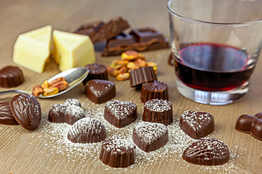 Chocolate pralines of different shapes in a composition with pistachios, dark chocolate, white chocolate and red wine