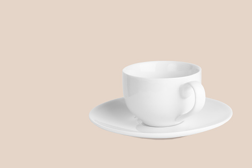 White coffee cup on saucer on a pale pink background.  Dishes for a coffee break. Color trend.