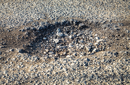 Close-up of a pot hole on the asphalt road surface.