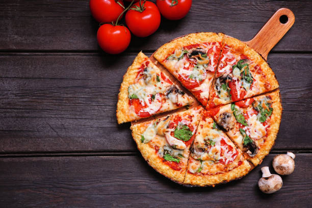 pizza saludable de corteza de coliflor sin gluten con tomates, champiñones y espinacas. escena de mesa de visión superior hacia abajo sobre madera oscura. - pizza fotografías e imágenes de stock