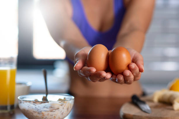 Sporty young woman showing egg with hands at home stock photo