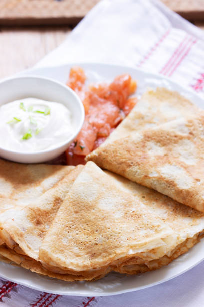 istock Thin pancakes with salmon and sour cream on a light background. Rustic style. 1307278331