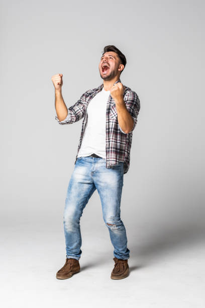 istock Casual handsome young man shouting for joy raising his hands above his head isolated on white background 1307278429