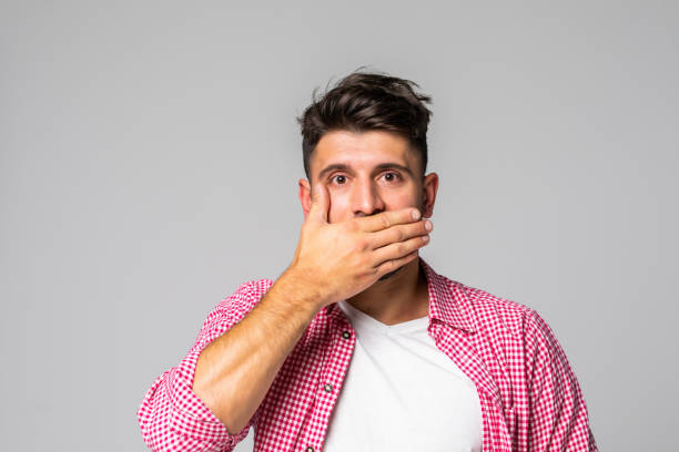 istock Surprised young man covering mouth with hand. Embarrassed handsome guy. Embarrassment concept. 1307278668
