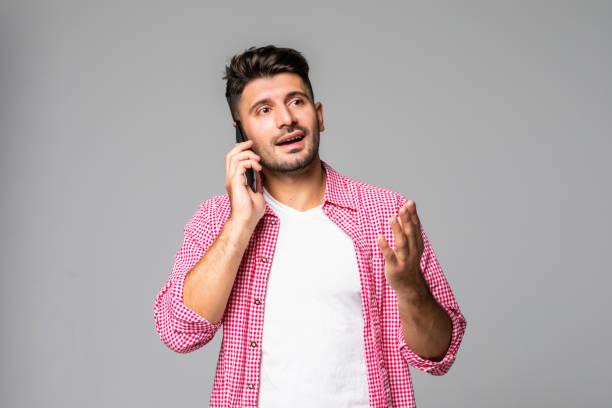 istock Smiling casual man talking on the phone isolated on gray background 1307279052