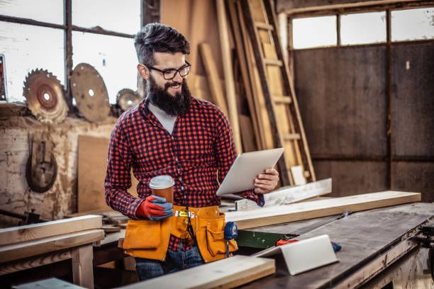 istock Young man at carpentry cutting wood and using digital tablet. 1307279897