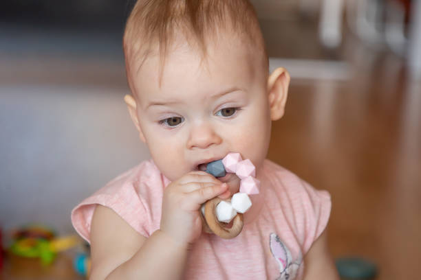 Little baby girl with teething toy Little baby girl with teething toy at home baby bracelet stock pictures, royalty-free photos & images