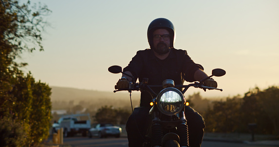 A lone motorcyclist looks forward as he rides down a smaller road in Ventura County, California.