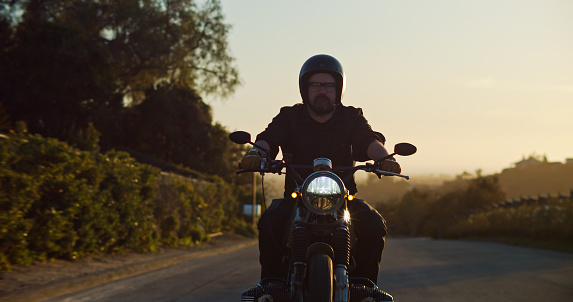 A lone motorcyclist looks forward as he rides down a smaller road in Ventura County, California.
