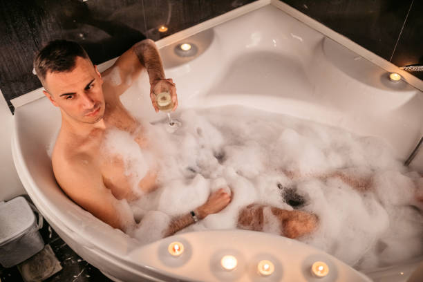 istock Young man drinking champagne in the bathtub 1307285582