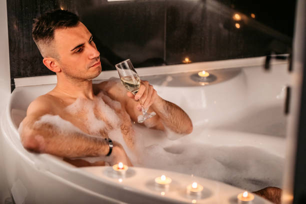 istock Young man drinking champagne in the bathtub 1307285729