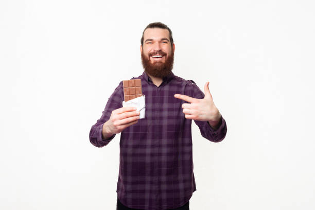 istock Smiling happy bearded man pointing at bar of chocolate 1307287923