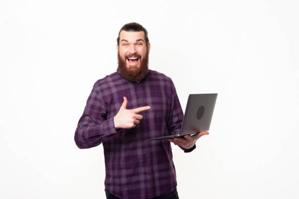 istock Amazed young bearded man pointing at laptop and smiling 1307287972