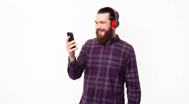 istock Happy young bearded man using smartphone and wearing headphones 1307288002