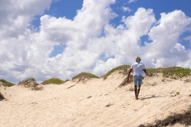 istock Lonely man with a cowboy hat walking on the sand on the beach 1307289536