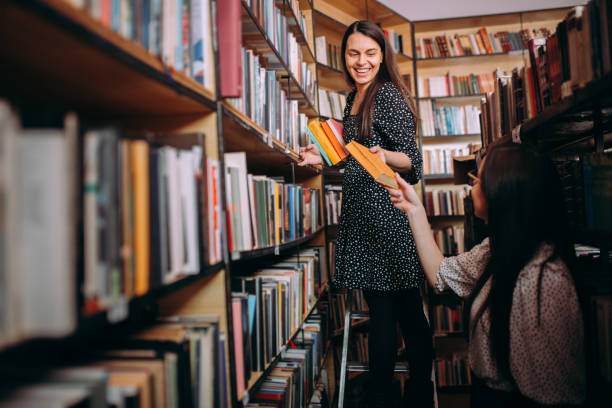 abgeschnittene erschossene junge frauen, die bücher in der heimbibliothek halten - bibliothekar stock-fotos und bilder