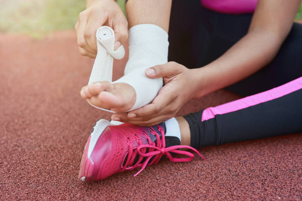 afro american girl putting bandage on injured foot - sprain imagens e fotografias de stock