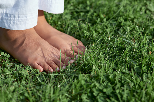 Close up of female child bare feet on green lawn in park