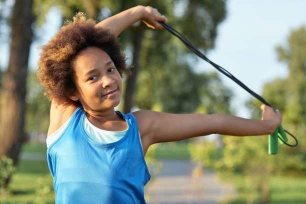 Portrait of young beautiful woman stretching and exercising outdoors on sport field using resistance band