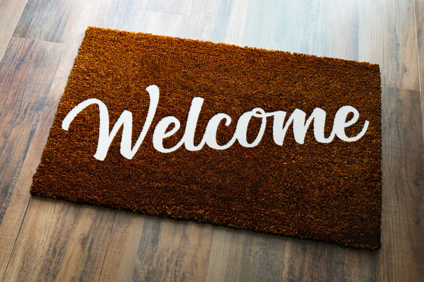 tappeto di benvenuto marrone scuro su sfondo pavimento in legno. - welcome sign doormat greeting floor mat foto e immagini stock