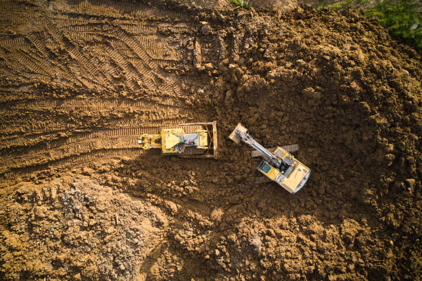 luftaufnahme von bagger und planierraupe auf der baustelle - graben körperliche aktivität stock-fotos und bilder