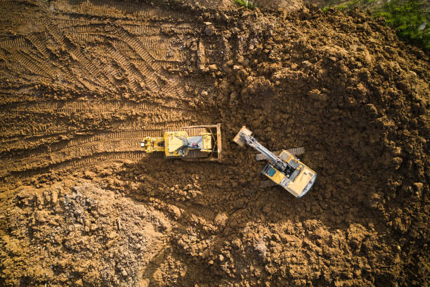 Aerial view of excavator and bulldozer on construction site Bulldozer is scraping a layer of soil and excavator is digging and dumping dirt caterpillar photos stock pictures, royalty-free photos & images