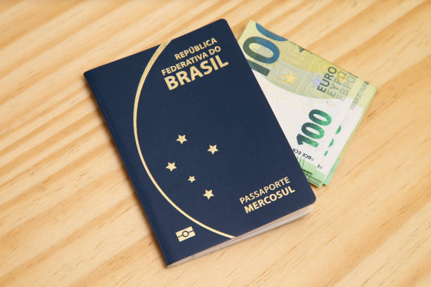 istock Passport with 100 euro banknotes on the side, on wooden table. 1307299700