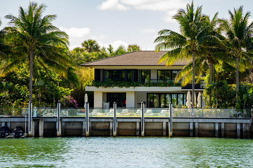 Miami, FL, USA - March 13, 2021: Luxury mansion Miami Beach scene waterfront view with palm trees