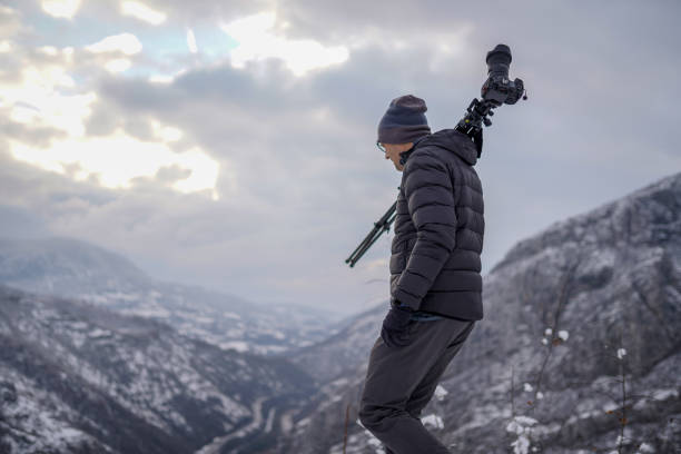 istock Photographer carrying tripod with camera on shoulder while walking across mountain 1307300780
