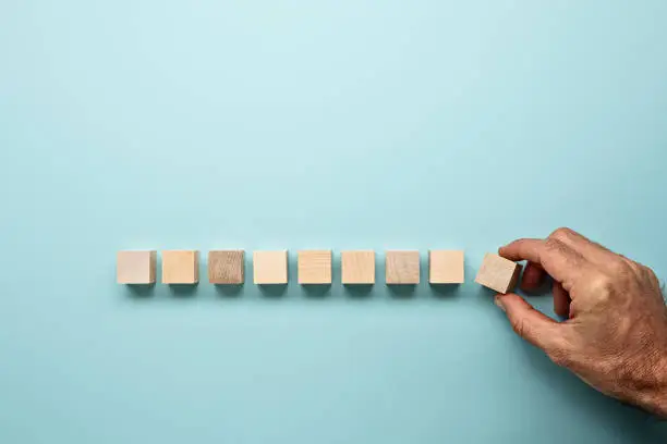 Blocks in a row on a blue background with mans hand
