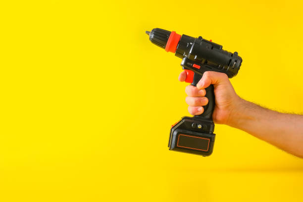 istock Cordless screwdriver on yellow background with cropped male hand 1307302377