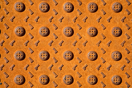 Rusted manhole cover with pattern.