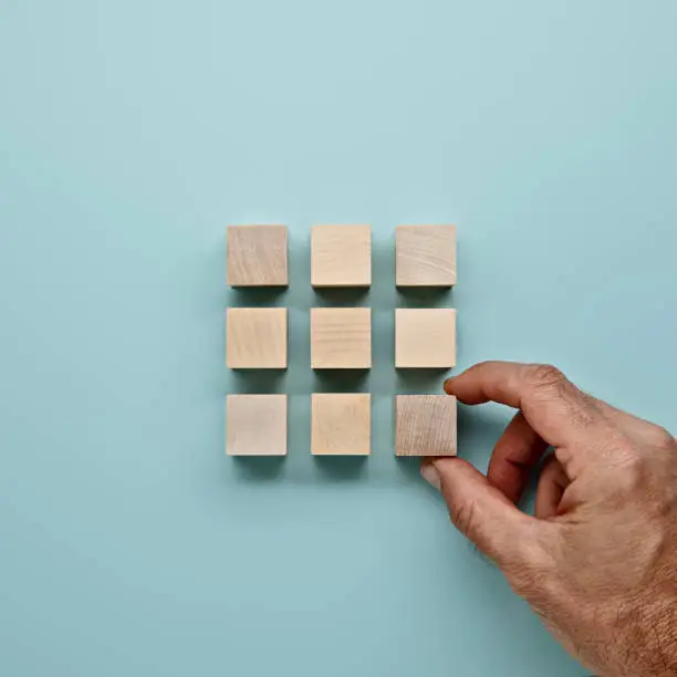 Blocks in a square on a blue background with mans hand