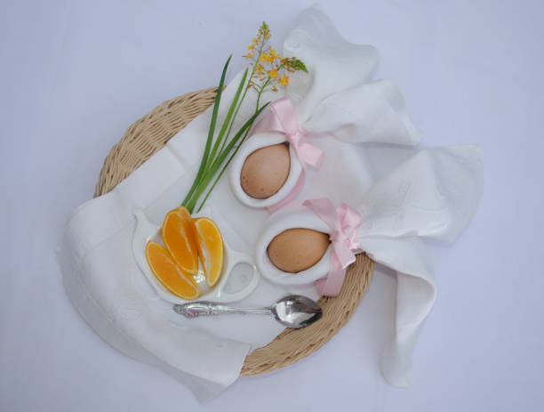 istock Beautiful festive Easter brunch with eggs in  napkin bunny, oranges and flowers on a basket. Traditional holiday on white background. 1307306558