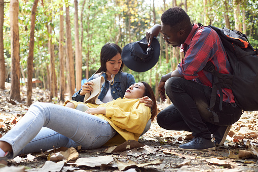 Tourists or hikers are helping to provide first aid to a friend who fainted while hiking.