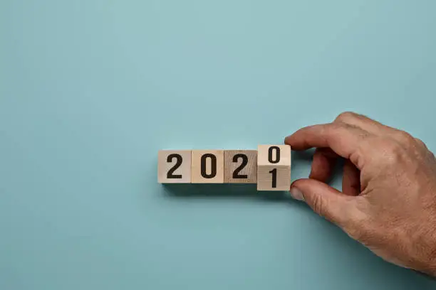 Hand flipping over wooden block of 2020 to 2021, New Year Resolutions, business concept stock photo