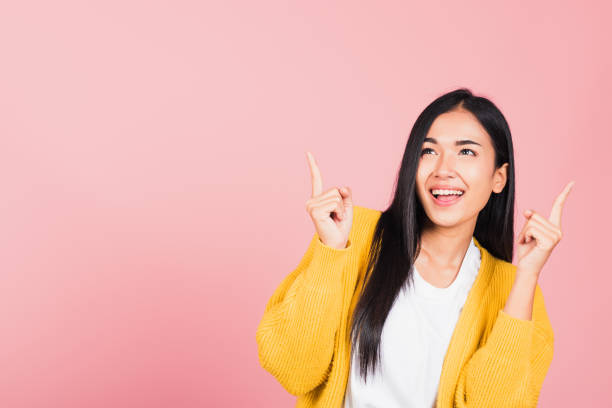 istock woman standing makes gesture two fingers point upwards above presenting product something 1307312021