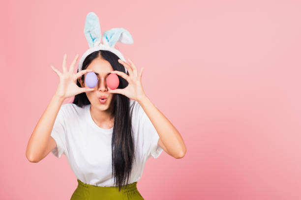 woman smiling wearing rabbit ears holding colorful Easter eggs front eyes