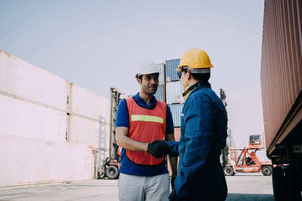 istock worker staff shaking hand for sucess working at Container. workers prepare export products. Container Shipping Logistics Engineering of Import Export Transportation Industry 1307324383