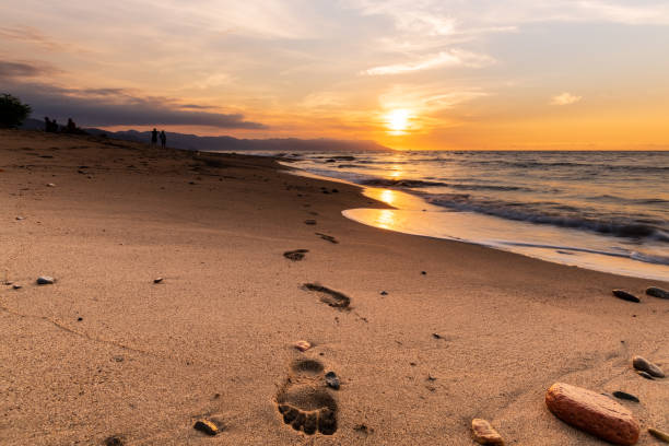 istock Sunset Ocean Footprints In The Sand 1307325124