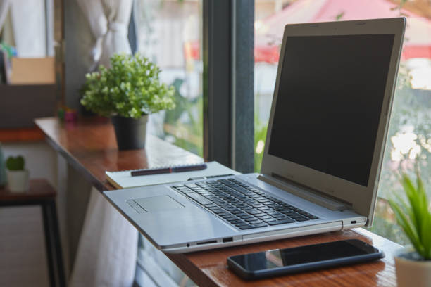 istock Laptop Computer and Smartphone on Wood Table in Coffee Shop Scene 1307325272