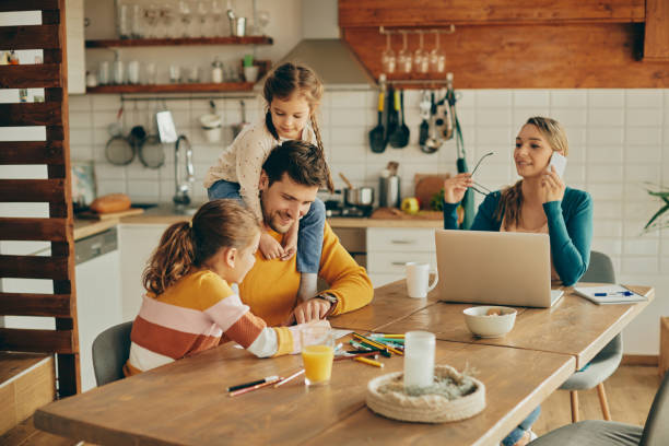istock Happy father having fun with daughters while mother is working at home. 1307328044