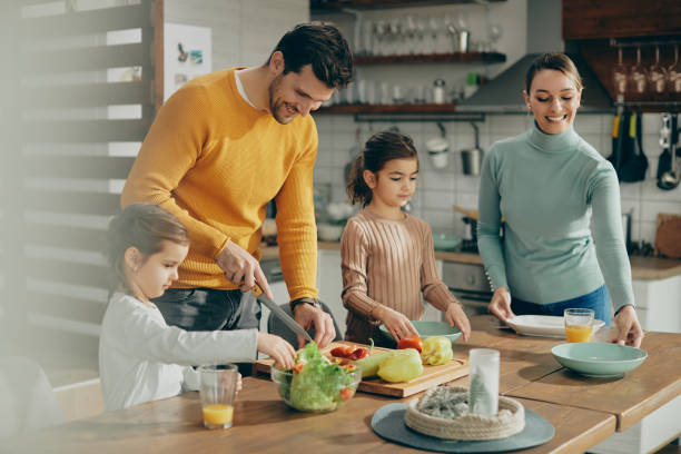 istock Happy parents and daughters preparing meal in the kitchen. 1307328604