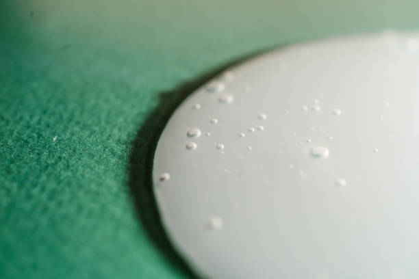 A drop of shampoo with bubbles on a green background. Demonstrates the texture of the product. Close-up.