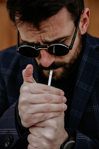 Businessman lighting up a cigarette after a workday.